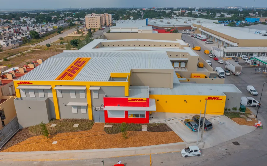Fotografía del proyecto DHL del portafolio LUCONSA: fachada amarilla, roja y gris del edificio con jardín frontal