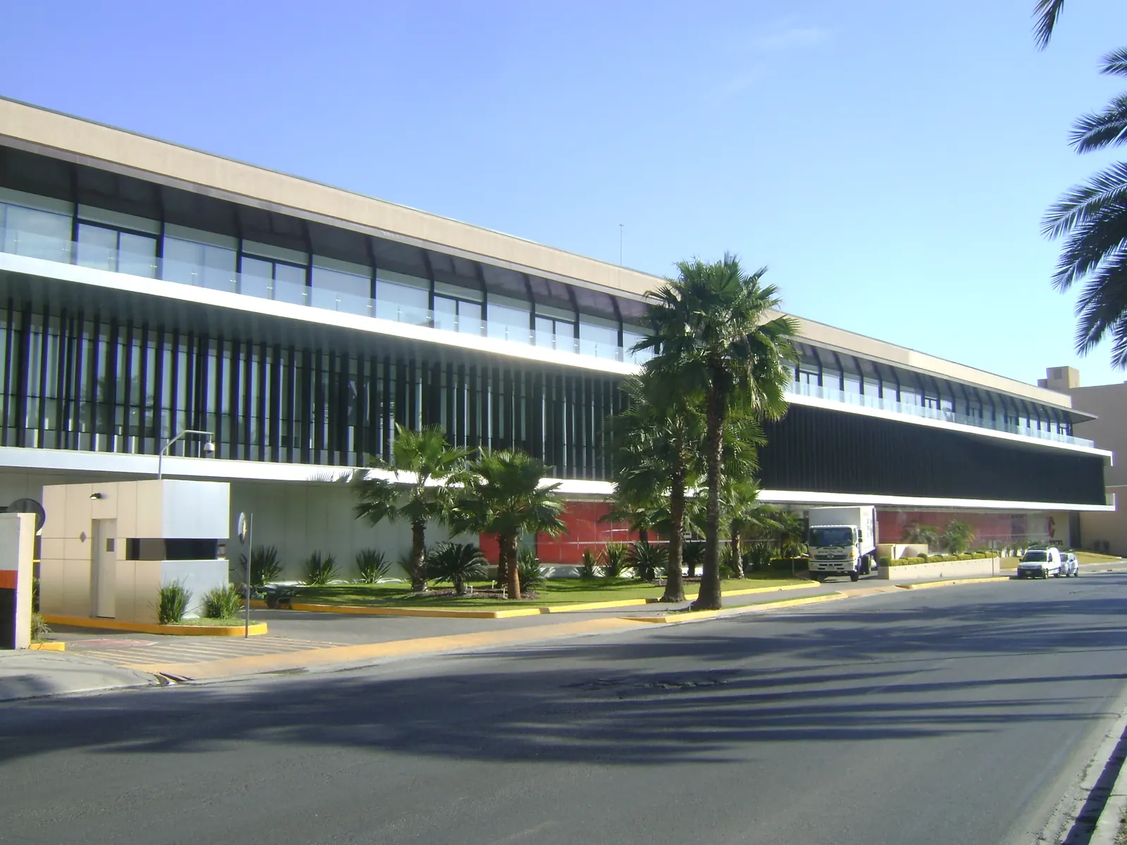 Fotografía del proyecto Arca Continental del portafolio LUCONSA: edificio corporativo de fachada horizontal con palmeras al frente