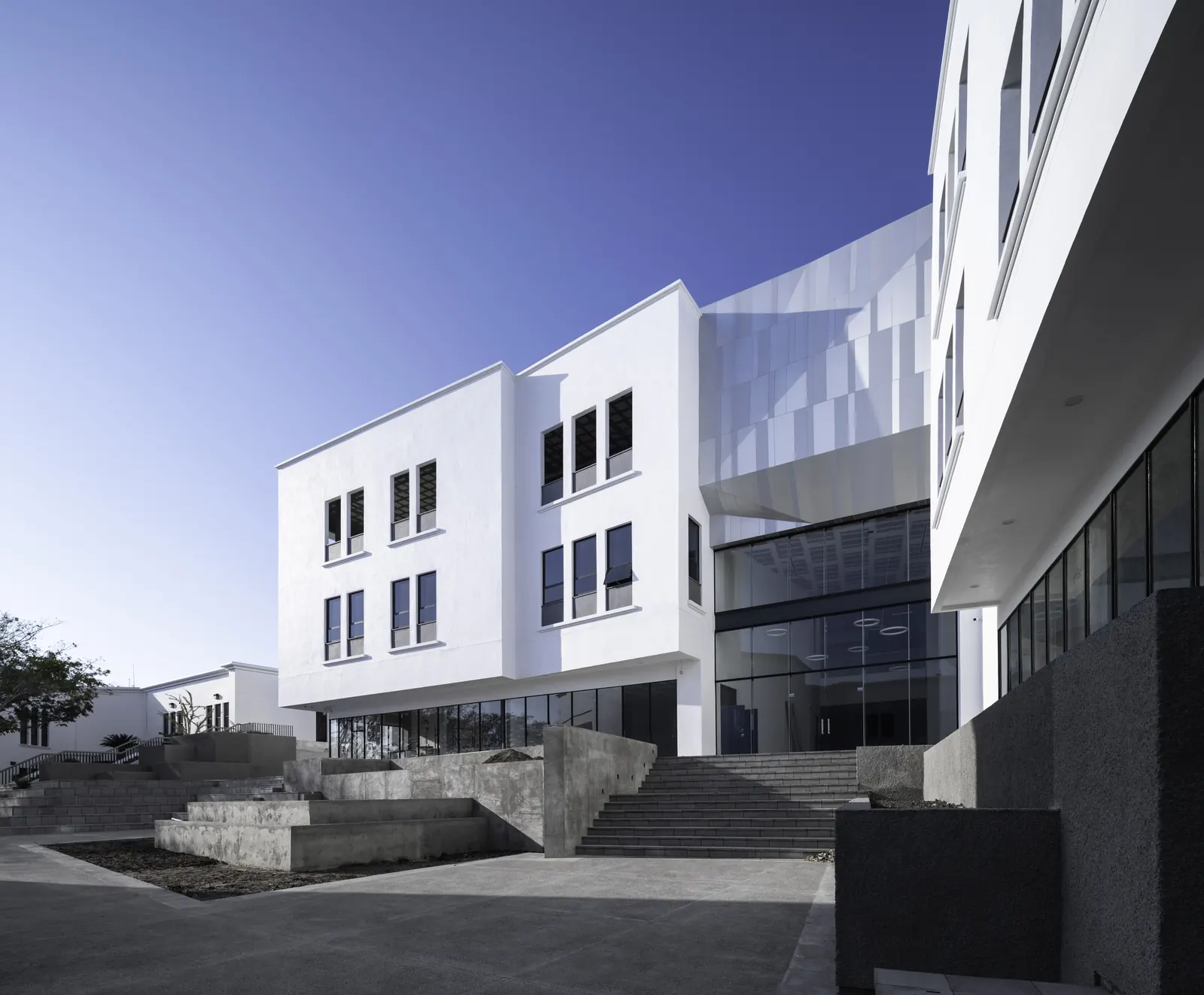 Fotografía del proyecto Colegio Americano del portafolio LUCONSA: edificio blanco con escalinata y fachada metálica