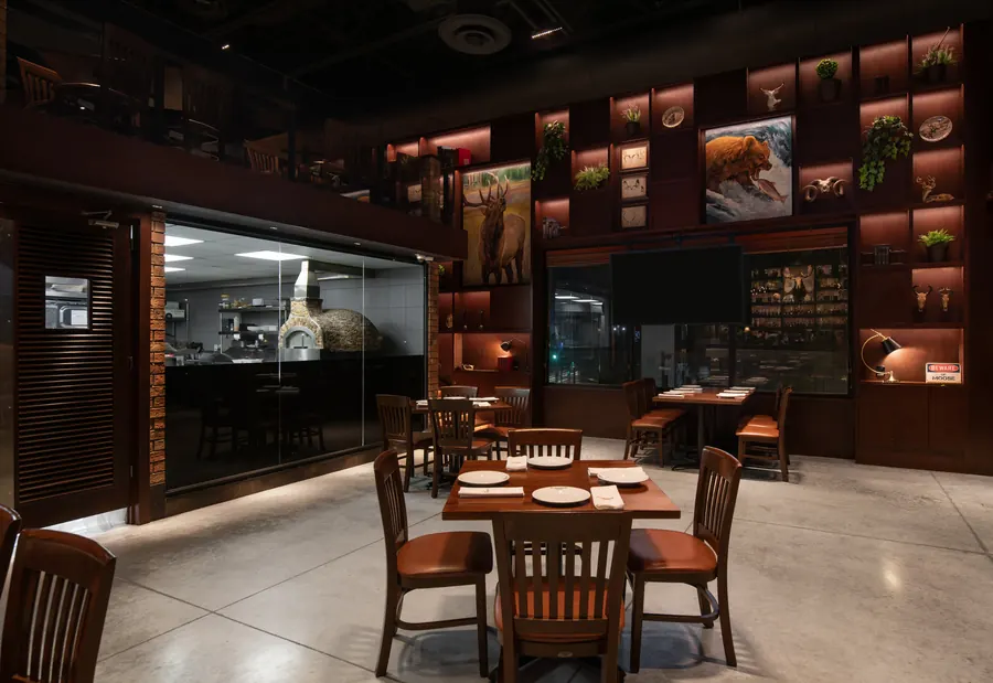Fotografía del proyecto El Asador Terraza del portafolio LUCONSA: salón con mesas de madera y estantería iluminada