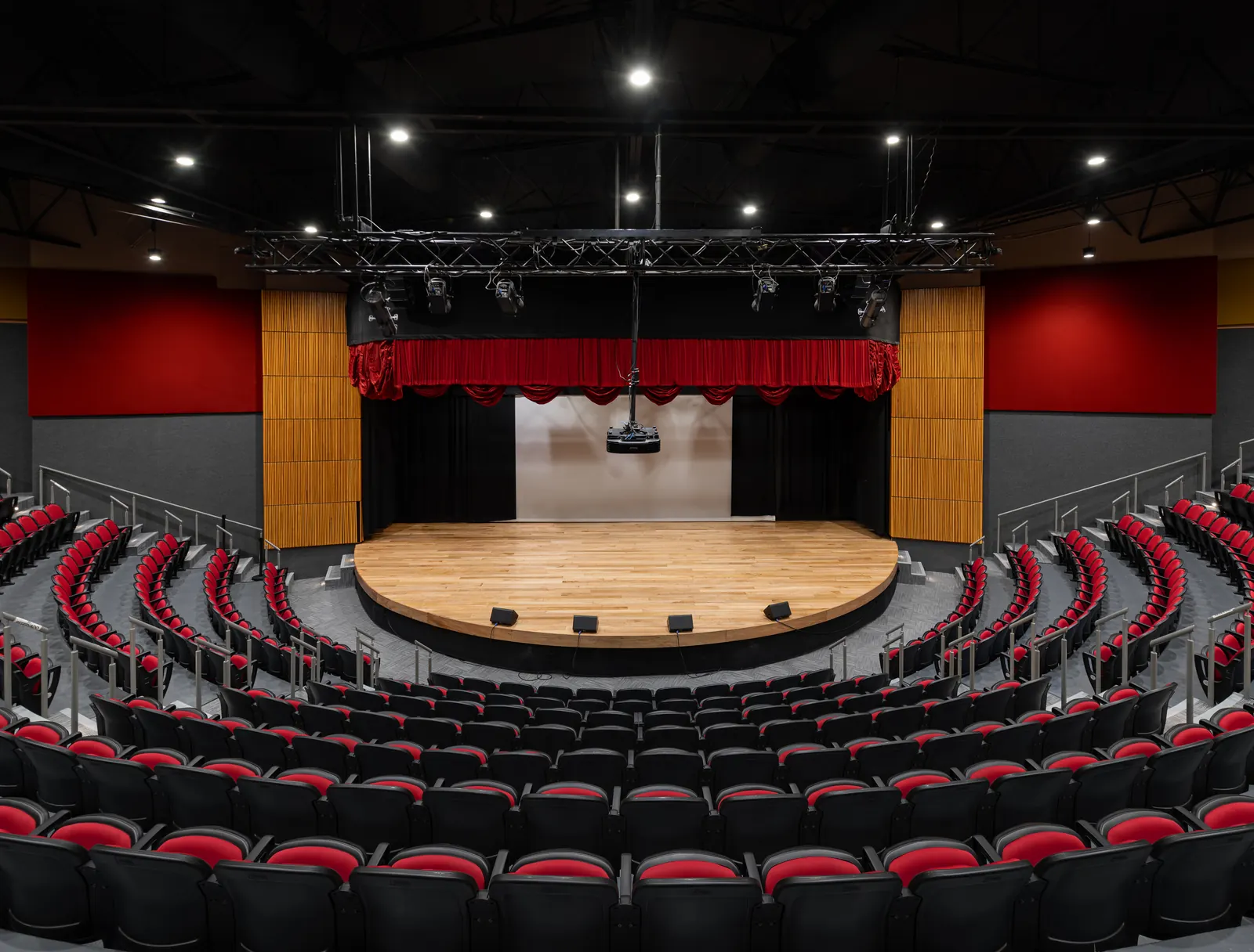 Fotografía del proyecto ICT Teatro del portafolio LUCONSA: sala con butacas rojas en gradería y escenario de duela