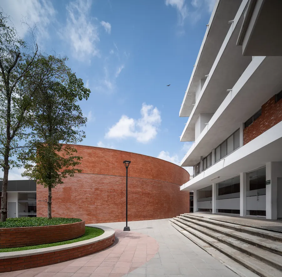 Fotografía del proyecto ICT Teatro del portafolio LUCONSA: fachada curva de ladrillo junto al edificio escolar
