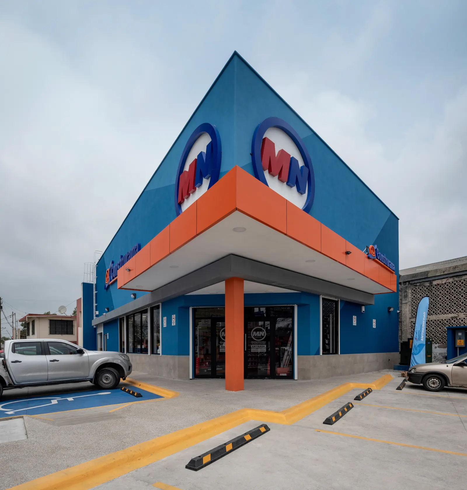 Fotografía del proyecto MN Express del portafolio LUCONSA: fachada con marquesina naranja y azul