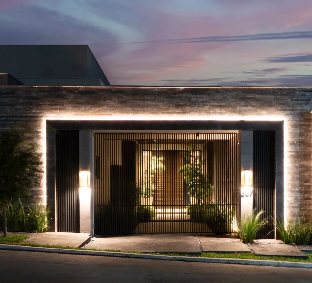 Fotografía del proyecto Residencias del portafolio LUCONSA: acceso principal con marco de piedra iluminado y celosía metálica
